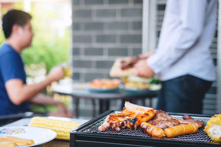 Group of friends Two young man enjoying grilled meat and raise a glass of beer to celebrate the...