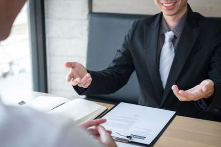 Employer or recruiter holding reading a resume during about colloquy his profile of candidate, employer in suit is conducting a job interview, manager resource employment and recruitment concept.の写真素材