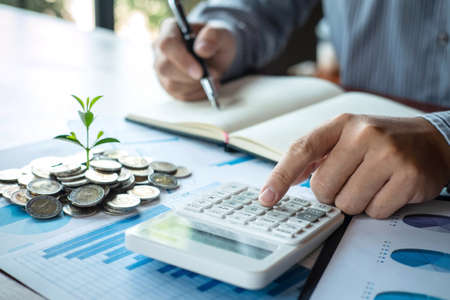 Businessman accountant making notes at report doing finances and calculate about cost of investment...