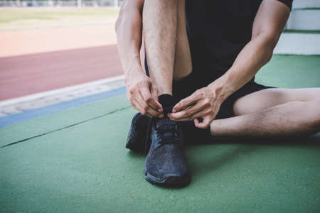 Young fitness athlete man running on road track, exercise workout wellness and runner tying shoelaces with copy space before run.の写真素材