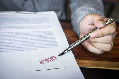 Close up hands of businessman pointing to signing and stamp on paper document to approve business...