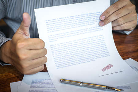 Hands of businessman stamp on paper document to approve business investment contract agreement.