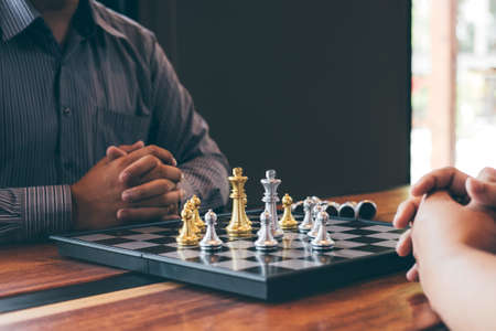 Intelligent businessman playing chess game competition with the opposite team, planning business...