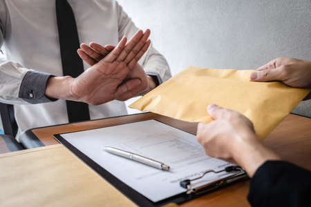 Anti bribery and corruption concept, Business man refusing and don't receive money banknote in envelop offer from business people to accept agreement contract of investment deal.の写真素材