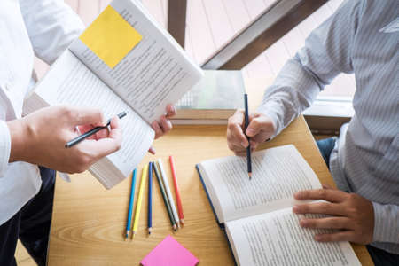 Tutor, learning, education, Group of teenager learning studying new lesson to knowledge in library during helping teaching friend education prepare for exam, youth campus friendship teens concept.の写真素材