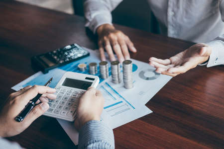 Business group brainstorming on meeting to planning project finance analyzing calculate with report document, stacking coins for step up growing business to profit and saving with wealth management.の写真素材