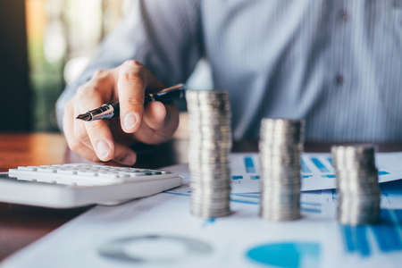 Businessman accountant counting money and making notes at report doing finances and calculate about cost of investment and analyzing financial data, Financing Accounting Banking Concept.の写真素材
