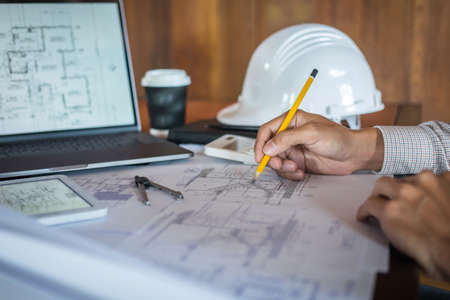 Construction engineering or architect hands working on blueprint inspection in workplace, while checking information drawing and sketching for architecture project working.の写真素材