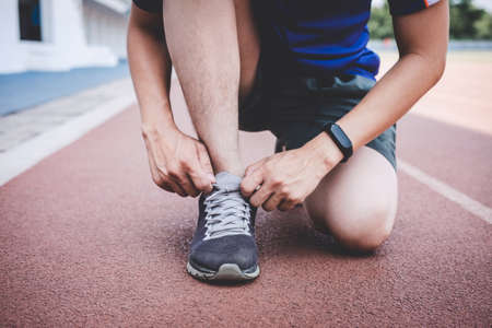 Young fitness athlete man running on road track, exercise workout wellness and runner tying shoelaces with copy space before run.の写真素材