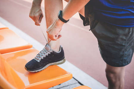 Young fitness athlete man running on road track, exercise workout wellness and runner tying shoelaces with copy space before run.の写真素材