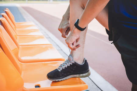 Young fitness athlete man running on road track, exercise workout wellness and runner tying shoelaces with copy space before run.の写真素材