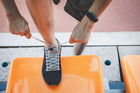 Young fitness athlete man running on road track, exercise workout wellness and runner tying shoelaces with copy space before run.の写真素材