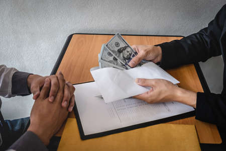 Dishonest cheating in business illegal money, Businessman giving bribe money in envelope to business people to give success the deal contract of investment, Bribery and corruption concept.の写真素材