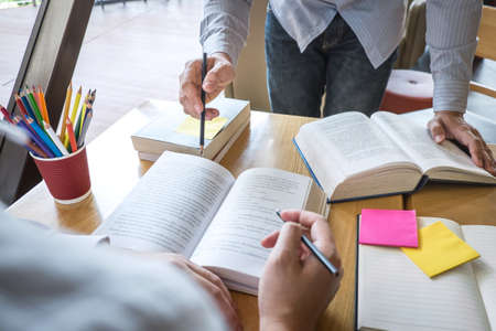 Group of young people learning studying new lesson to knowledge in library during helping teaching friend education prepare for exam, youth campus friendship teenager teens concept.の写真素材