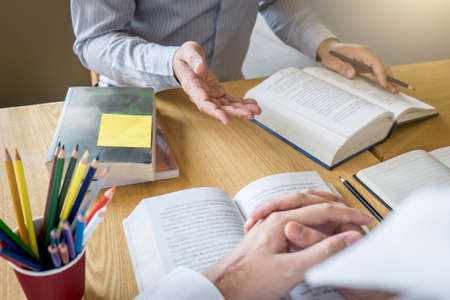 Tutor, learning, education, Group of teenager learning studying new lesson to knowledge in library during helping teaching friend education prepare for exam, youth campus friendship teens concept.の写真素材
