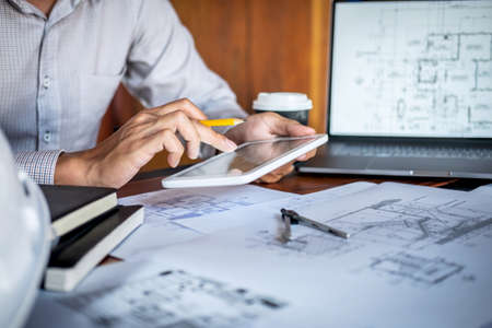 Construction engineering or architect hands working on blueprint inspection in workplace, while checking information drawing and sketching for architecture project working.の写真素材