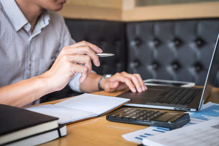 Businessman working investment project on laptop computer with report document and analyze, calculating financial data on graph documents, doing finance making statistics.の写真素材