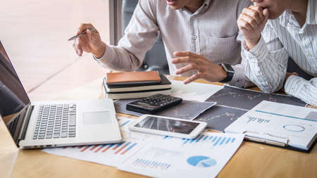 Stock exchange market concept, Team of investment trading or stock brokers having a consultation and analyzing with display screen and pointing on the data presented and deal on a stock exchange.の写真素材