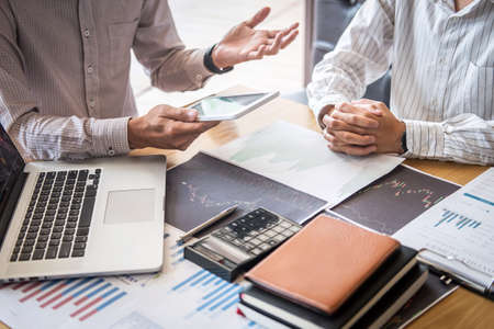 Stock exchange market concept, Team of investment trading or stock brokers having a consultation and analyzing with display screen and pointing on the data presented and deal on a stock exchange.の写真素材