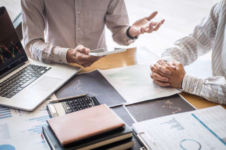 Stock exchange market concept, Team of investment trading or stock brokers having a consultation and analyzing with display screen and pointing on the data presented and deal on a stock exchange.の写真素材