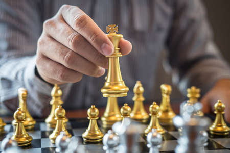 Gold and silver chess with player, Intelligent businessman playing chess game competition to planning business strategic to development for win and success.の写真素材