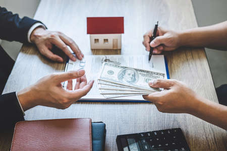 Estate agent broker receive money from client after signing agreement contract real estate with approved mortgage application form, buying or concerning mortgage loan offer for and house insurance.の写真素材