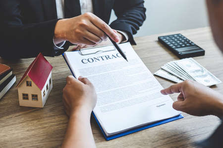 Estate agent broker reach contract form to client signing agreement contract real estate with approved mortgage application form, buying or concerning mortgage loan offer for and house insurance.の写真素材