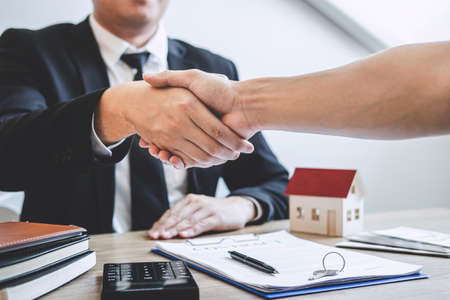 Finishing to successful deal of real estate, Broker and client shaking hands after signing contract approved application form, concerning mortgage loan offer for and house insurance.の写真素材