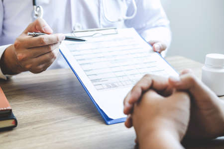 Professional doctor in white uniform gown coat and patient discussing consults to treatment of symptom disease and making prescriptions.の写真素材