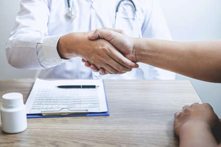 Doctor having shaking hands to congrats with patient after recommend treatment while discussing explaining his symptoms and counsel diagnosis health, healthcare and assistance concept.の写真素材