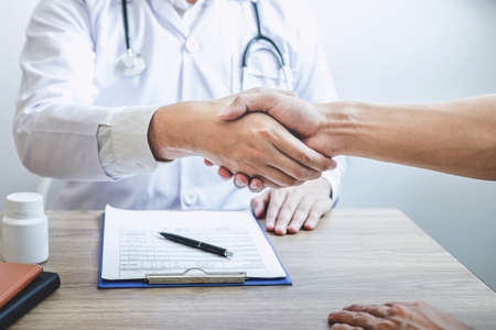 Doctor having shaking hands to congrats with patient after recommend treatment while discussing explaining his symptoms and counsel diagnosis health, healthcare and assistance concept.の写真素材