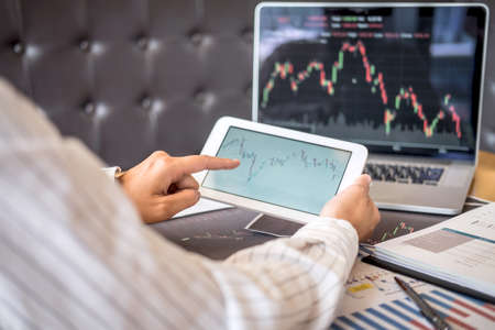 Stock exchange market concept, Business investor trading or stock brokers having a planning and analyzing with display screen and pointing on the data presented and deal on a stock exchange.の写真素材