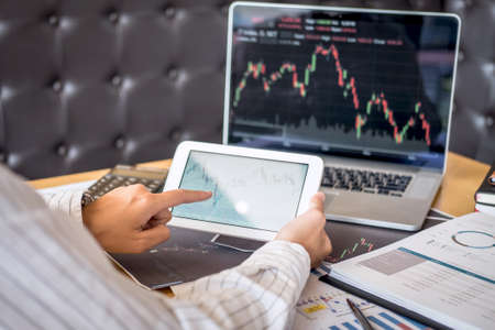 Stock exchange market concept, Business investor trading or stock brokers having a planning and analyzing with display screen and pointing on the data presented and deal on a stock exchange.の写真素材