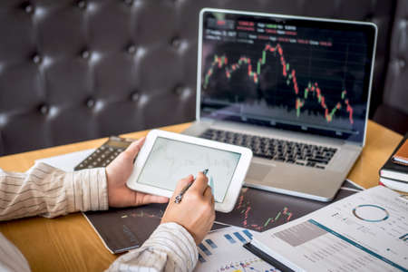 Stock exchange market concept, Business investor trading or stock brokers having a planning and analyzing with display screen and pointing on the data presented and deal on a stock exchange.の写真素材