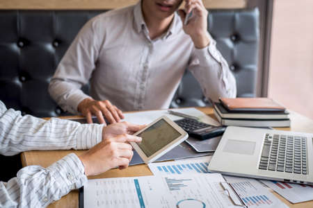 Stock exchange market concept, Team of investment trading or stock brokers having a consultation and analyzing with display screen and pointing on the data presented and deal on a stock exchange.の写真素材
