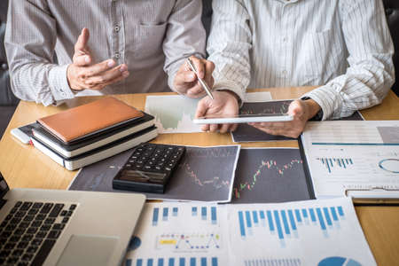 Stock exchange market concept, Team of investment trading or stock brokers having a consultation and analyzing with display screen and pointing on the data presented and deal on a stock exchange.の写真素材