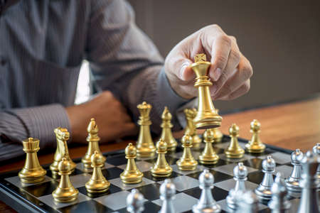 Gold and silver chess with player, Intelligent businessman playing chess game competition to planning business strategic to development for win and success.の写真素材