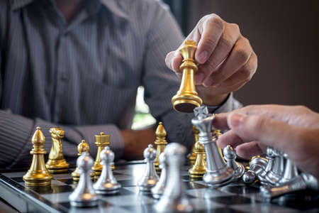 Intelligent businessman playing chess game competition with the opposite team, planning business strategic to development for win and success, Gold and silver chess with player.の写真素材