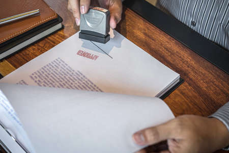 Hands of businessman stamp on paper document to approve business investment contract agreement.の写真素材