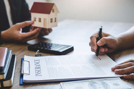 Estate agent giving house and keys to client after signing agreement contract real estate with approved mortgage application form, concerning mortgage loan offer for and house insurance.の写真素材