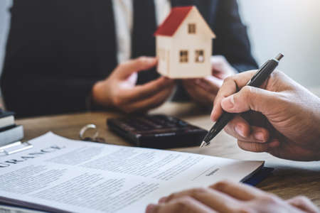 Estate agent giving house and keys to client after signing agreement contract real estate with approved mortgage application form, concerning mortgage loan offer for and house insurance.の写真素材