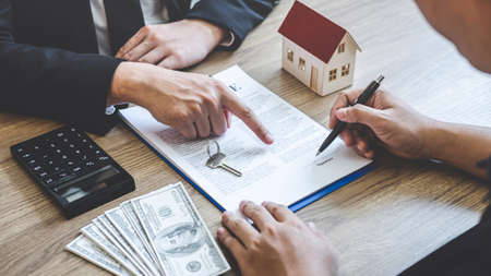 Estate agent broker reach contract form to client signing agreement contract real estate with approved mortgage application form, buying or concerning mortgage loan offer for and house insurance.の写真素材