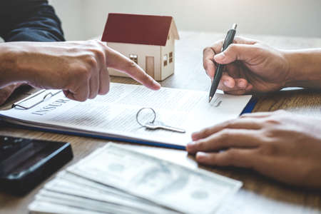 Estate agent broker reach contract form to client signing agreement contract real estate with approved mortgage application form, buying or concerning mortgage loan offer for and house insurance.の写真素材