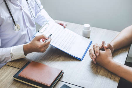 Professional doctor in white uniform gown coat and patient discussing consults to treatment of symptom disease and making prescriptions.の写真素材