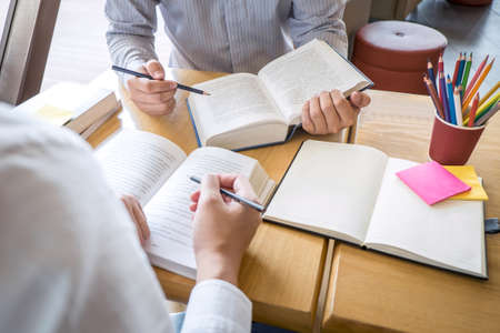 Tutor, learning, education, Group of teenager learning studying new lesson to knowledge in library during helping teaching friend education prepare for exam, youth campus friendship teens concept.の写真素材