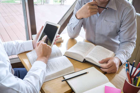 Tutor, learning, education, Group of teenager learning studying new lesson to knowledge in library during helping teaching friend education prepare for exam, youth campus friendship teens concept.の写真素材