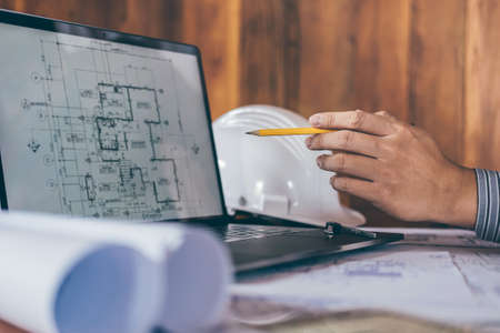Construction engineering or architect discussing a blueprint and building model while checking...