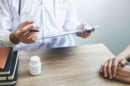Professional doctor in white uniform gown coat and patient discussing consults to treatment of symptom disease and making prescriptions.の写真素材
