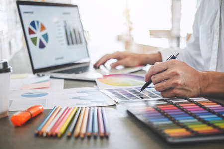 Young creative graphic designer working on project architectural drawing and color swatches,...
