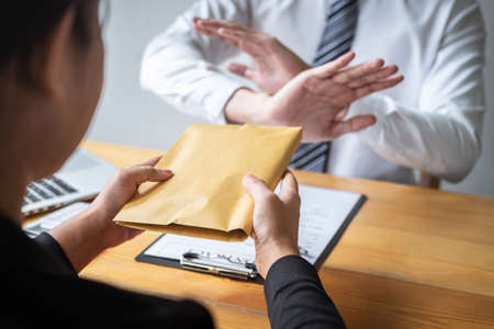 Anti bribery and corruption concept, Business man refusing and don't receive money banknote in envelope offer from business people to accept agreement contract of investment deal.の写真素材